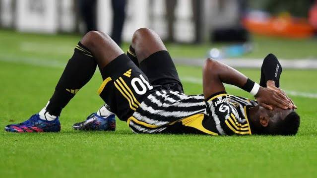 A picture of Juventus midfielder Paul Pogba lying on the field ground with his hands on his face 