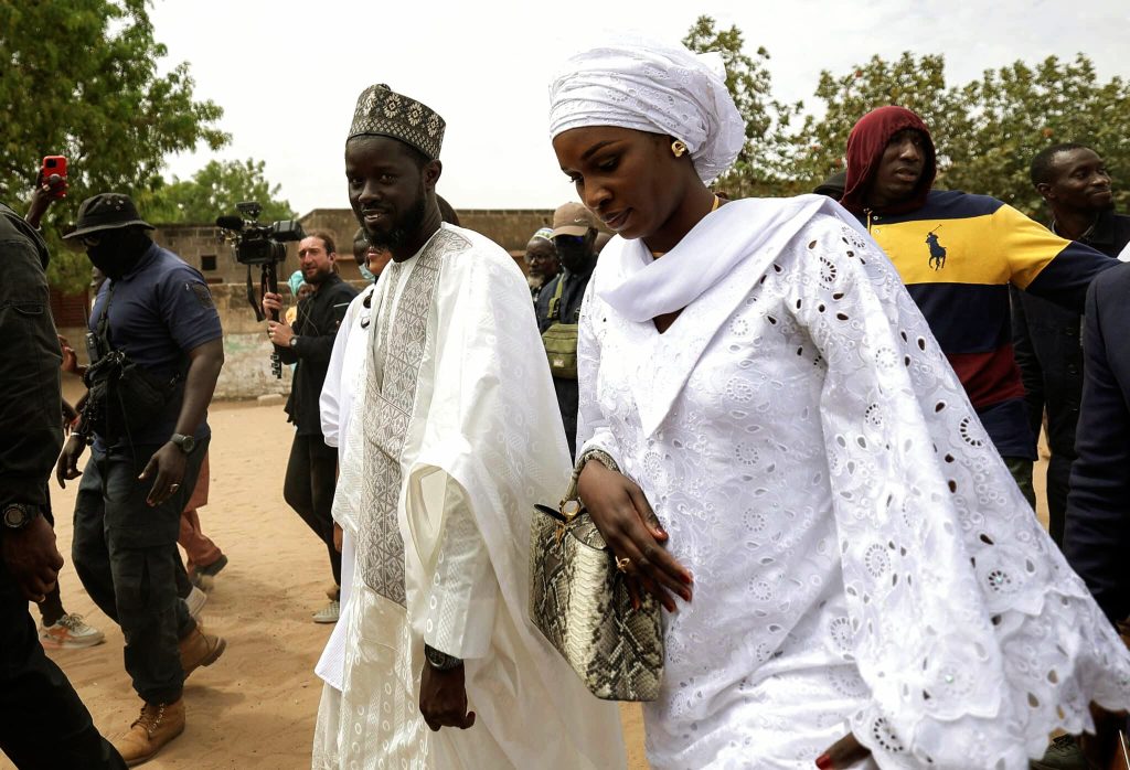 A picture of Bassirou Diomaye Faye and his wife walking alongside security personnels