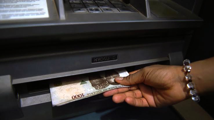 A picture of a customer's hand withdrawing money from an ATM machine 