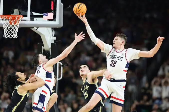 A picture of the UConn's team player in court playing with their opponent team members 
