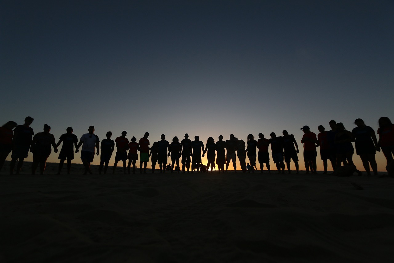 An image of a group of people of different generations with a shared cultural heritage holding hands 